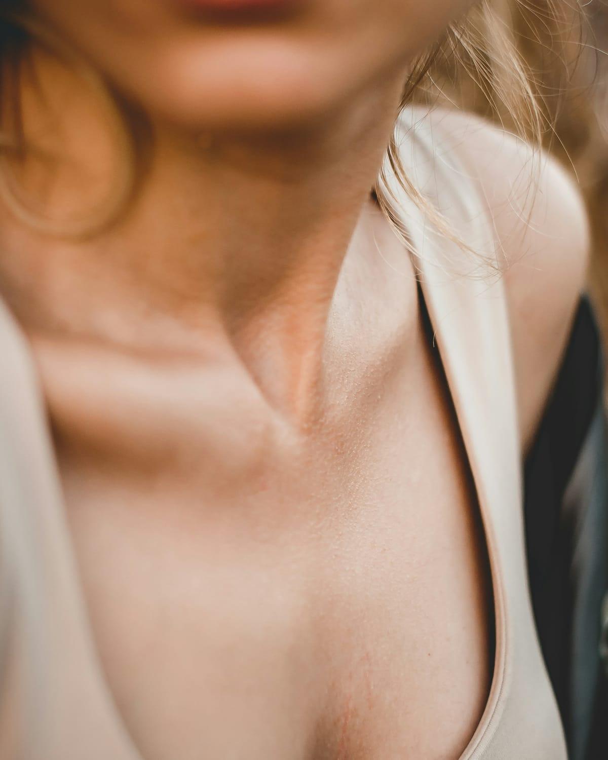 Close-up of a woman's neck and décolletage in warm, soft natural light